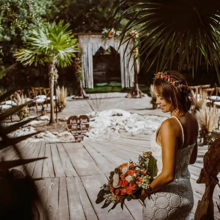A radiant bride in a white dress and flower crown smiles at the cenote wedding venue.