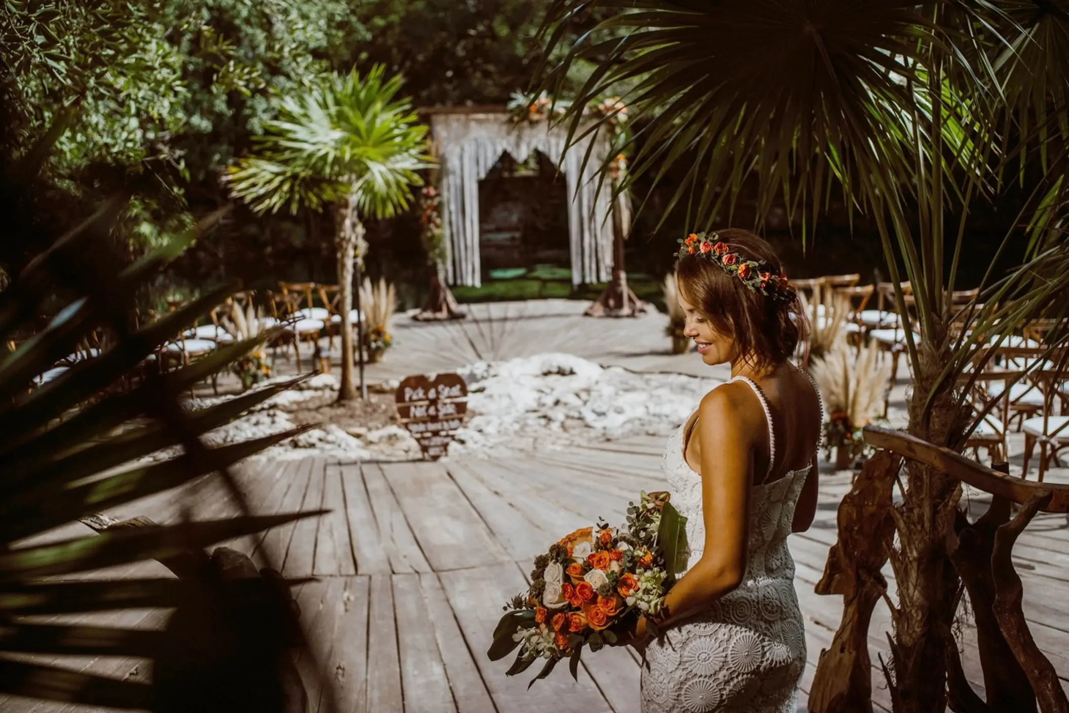 A radiant bride in a white dress and flower crown smiles at the cenote wedding venue.