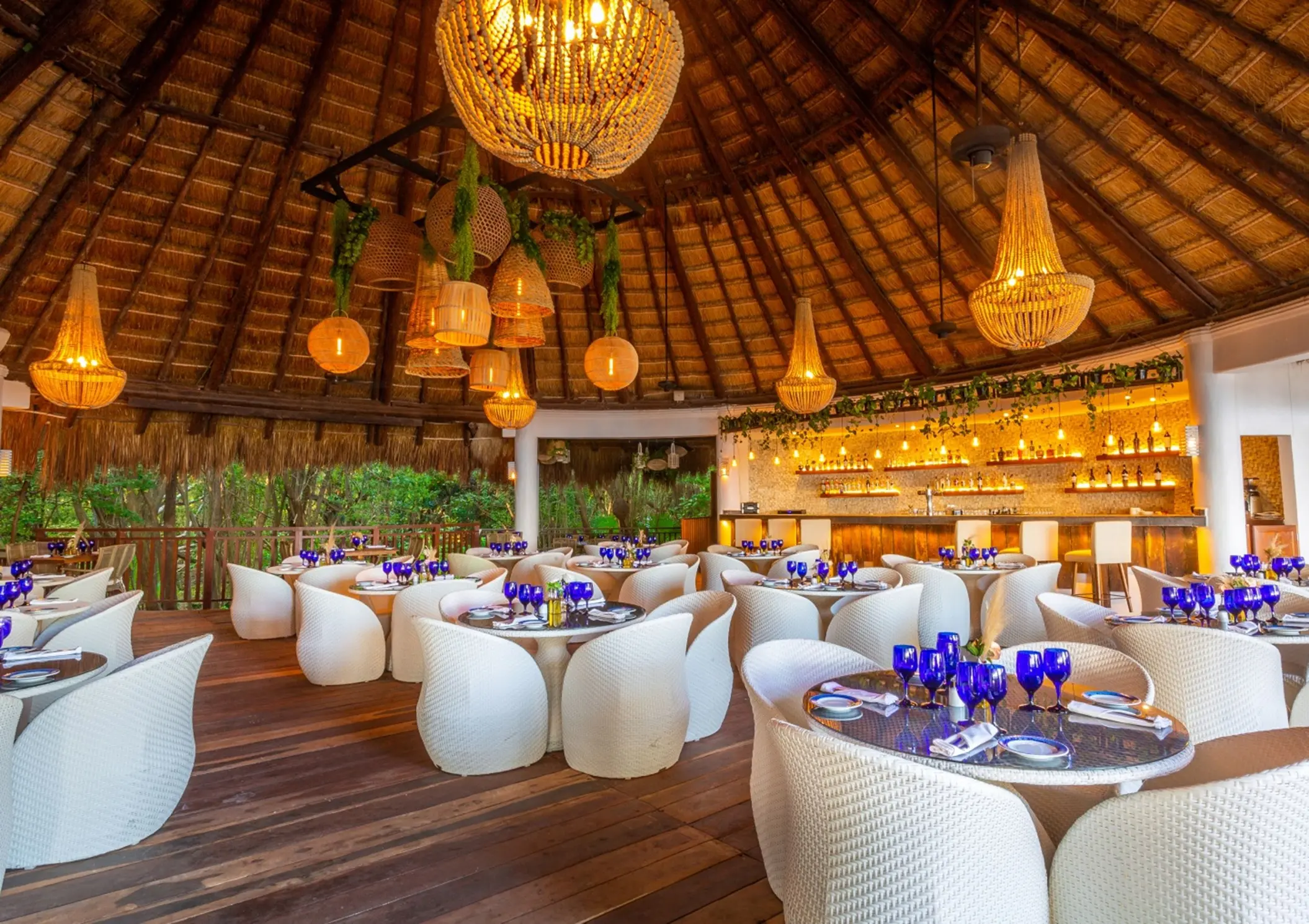 The Riviera restaurant at Sandos Caracol Eco Resort boasts a high thatched roof, chic lighting, and elegant dining.
