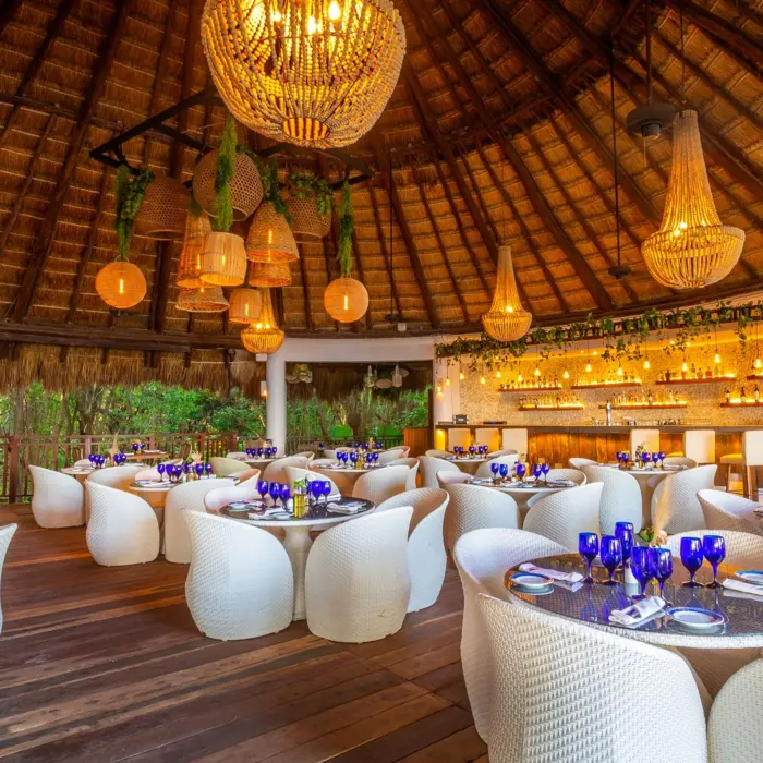 The Riviera restaurant at Sandos Caracol Eco Resort boasts a high thatched roof, chic lighting, and elegant dining.