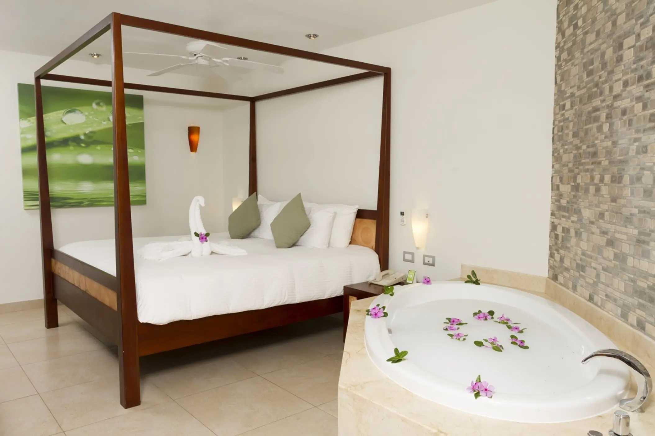 A suite at Sandos Caracol Eco Resort features a four-poster bed and a luxurious tub with flower petals.