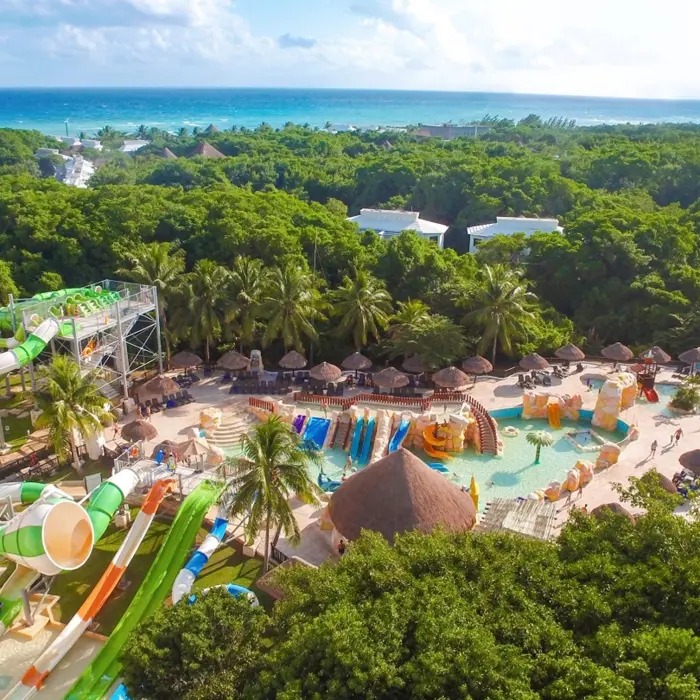 An aerial view of the vibrant water park at Sandos Caracol Eco Resort, surrounded by green nature and the ocean.