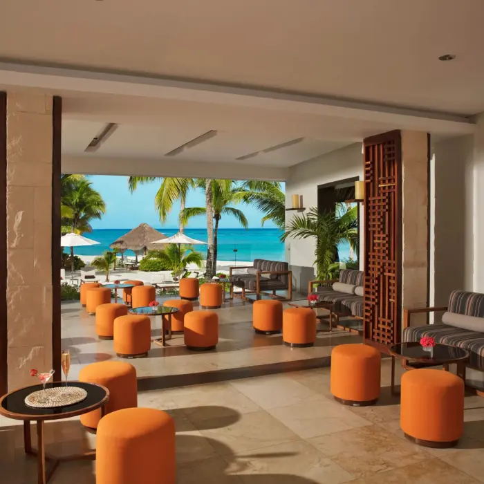 Elegant open-air lobby bar with marble floors, tropical views, and stylish furnishings at a luxury resort.