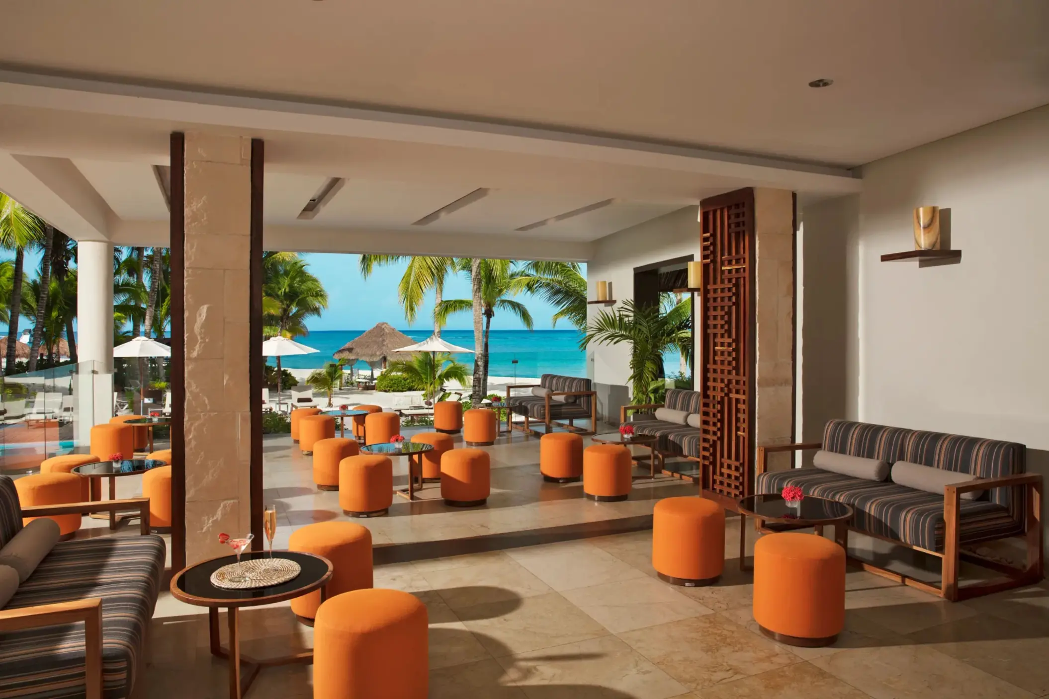 Elegant open-air lobby bar with marble floors, tropical views, and stylish furnishings at a luxury resort.