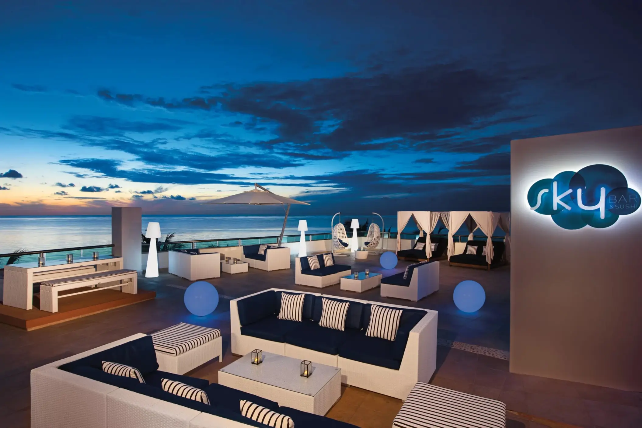 Sky Bar with panoramic rooftop views, comfortable seating, and glowing accent lights for sunset cocktails.