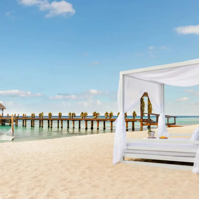Luxurious beachside Bali bed with ocean views and a romantic pier stretching over calm blue water.