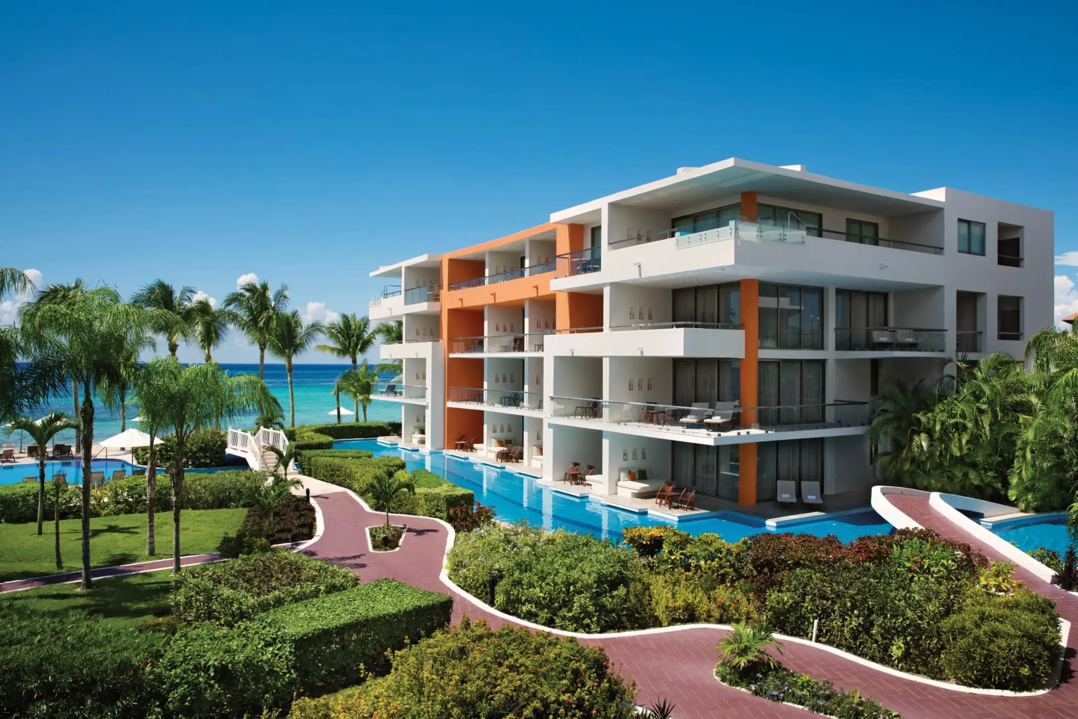 Contemporary four-story resort building with lush gardens and panoramic views of the Caribbean Sea.