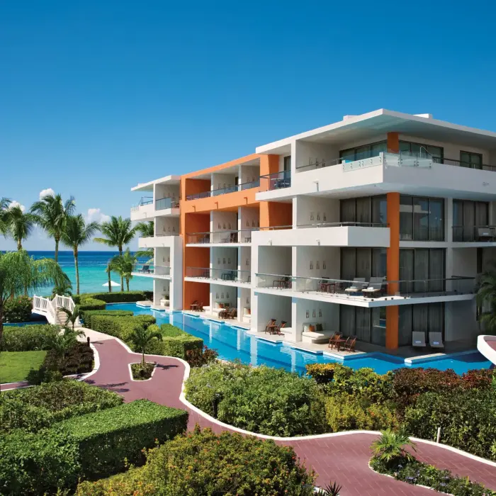 Contemporary four-story resort building with lush gardens and panoramic views of the Caribbean Sea.