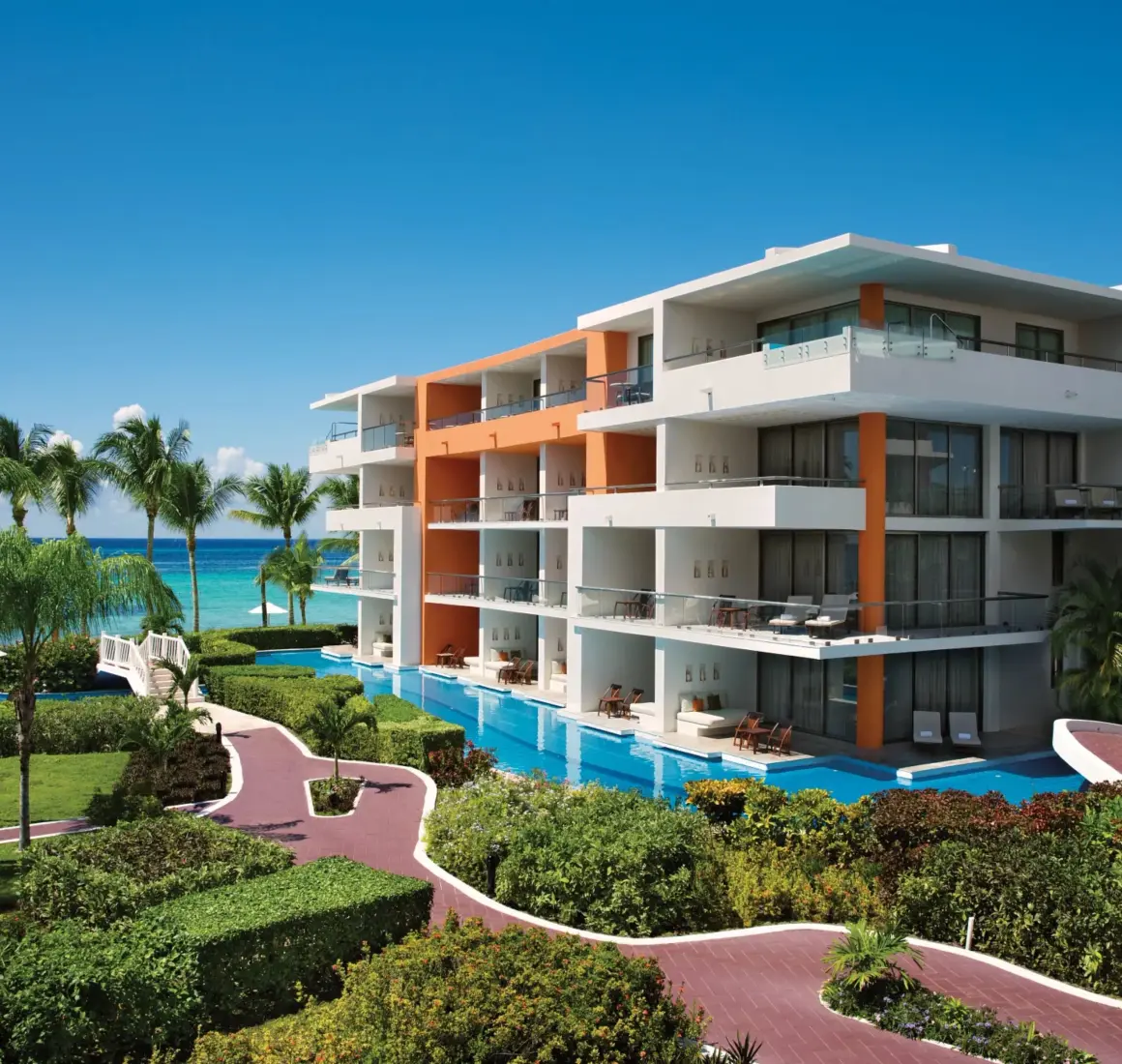 Contemporary four-story resort building with lush gardens and panoramic views of the Caribbean Sea.
