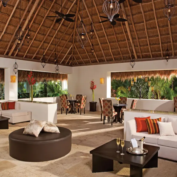 Spacious Preferred Club lounge with thatched roof, modern decor, and cozy seating areas by the bar.