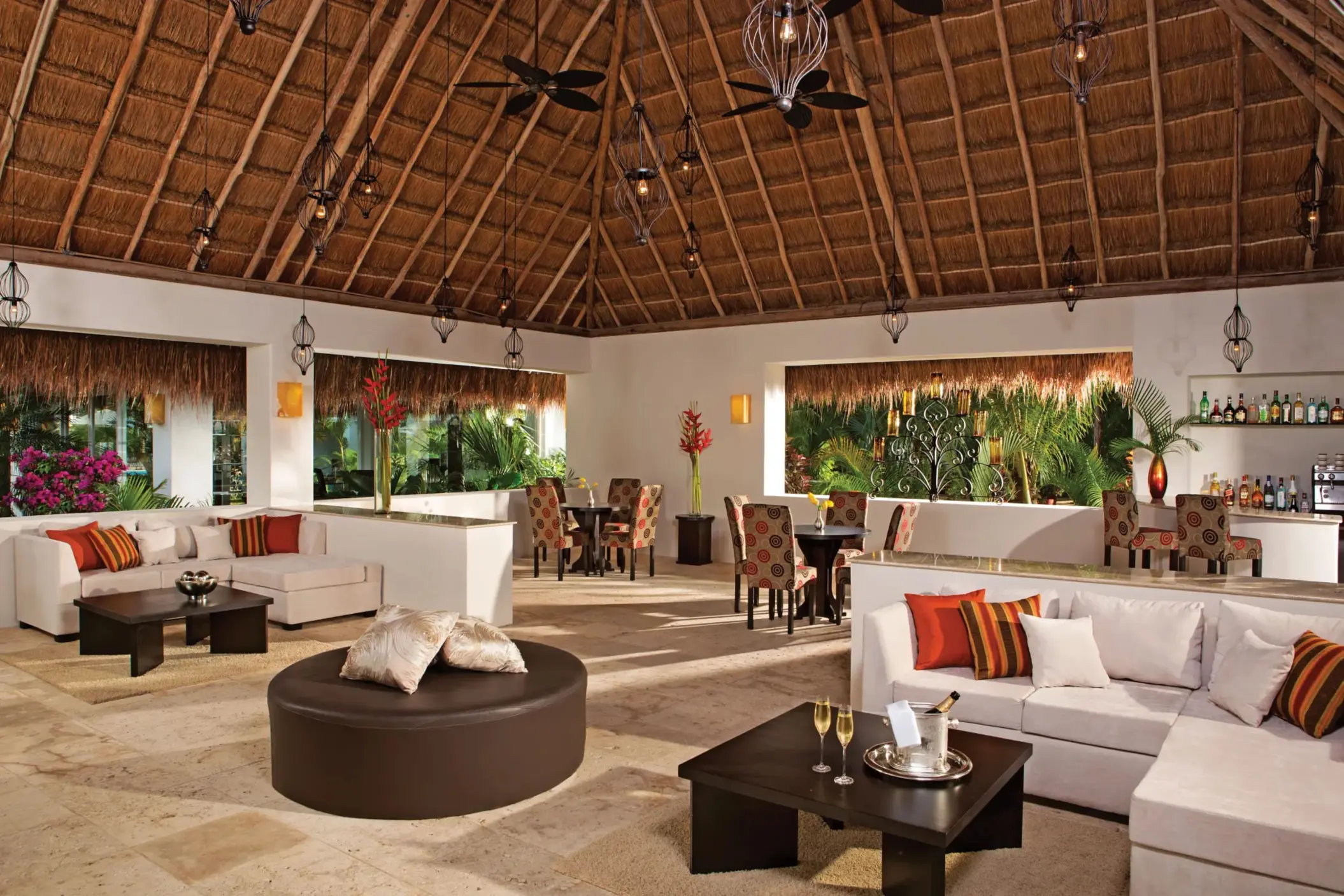 Spacious Preferred Club lounge with thatched roof, modern decor, and cozy seating areas by the bar.
