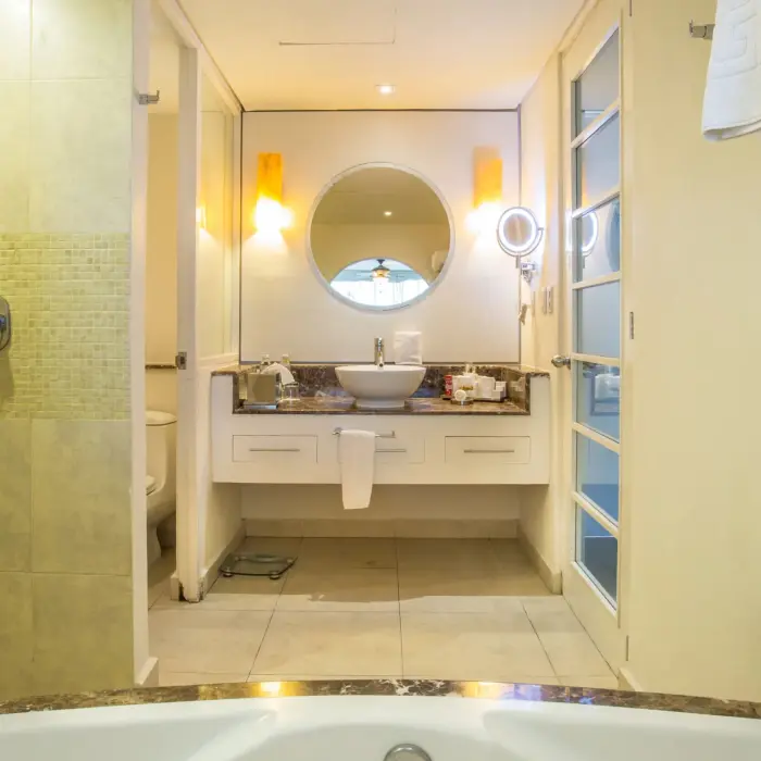 Marble-accented bathroom with soaking tub, walk-in shower, round mirror, and double-sink vanity area.