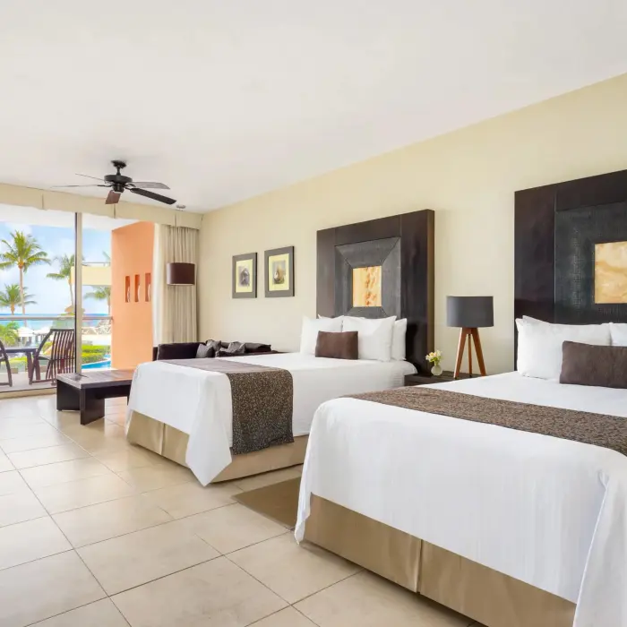 Spacious double-bed junior suite with ocean view balcony, modern decor, and seating area.