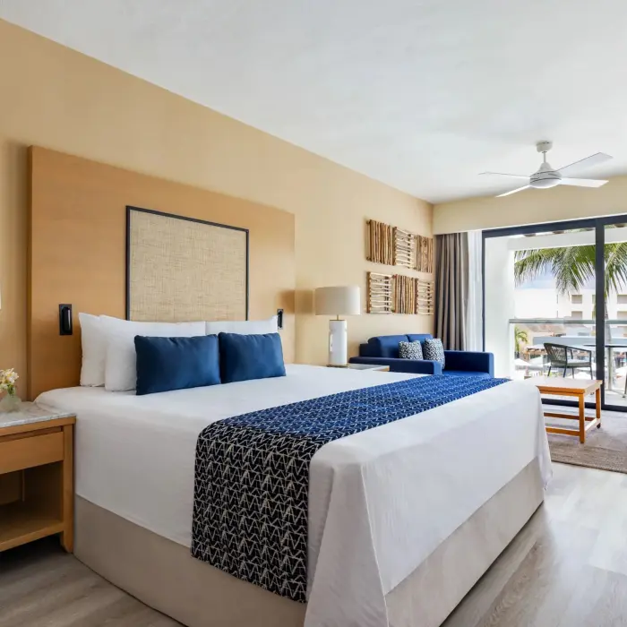 King bed junior suite with modern beach-inspired design, sitting area, and private garden view balcony.