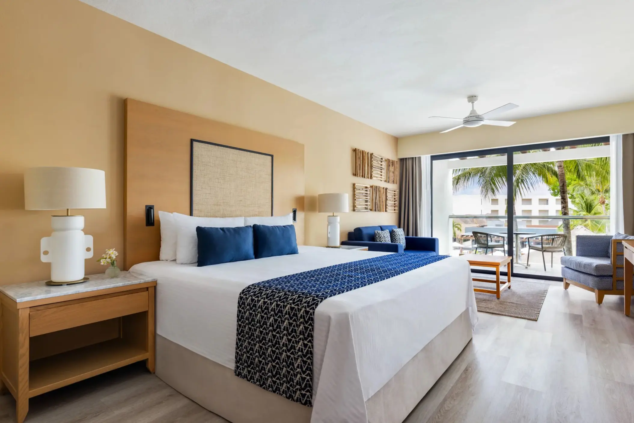 King bed junior suite with modern beach-inspired design, sitting area, and private garden view balcony.