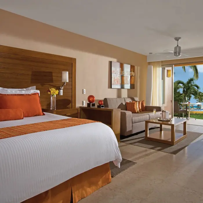 Preferred Club junior suite with king bed, stylish decor, and tropical pool view from patio.