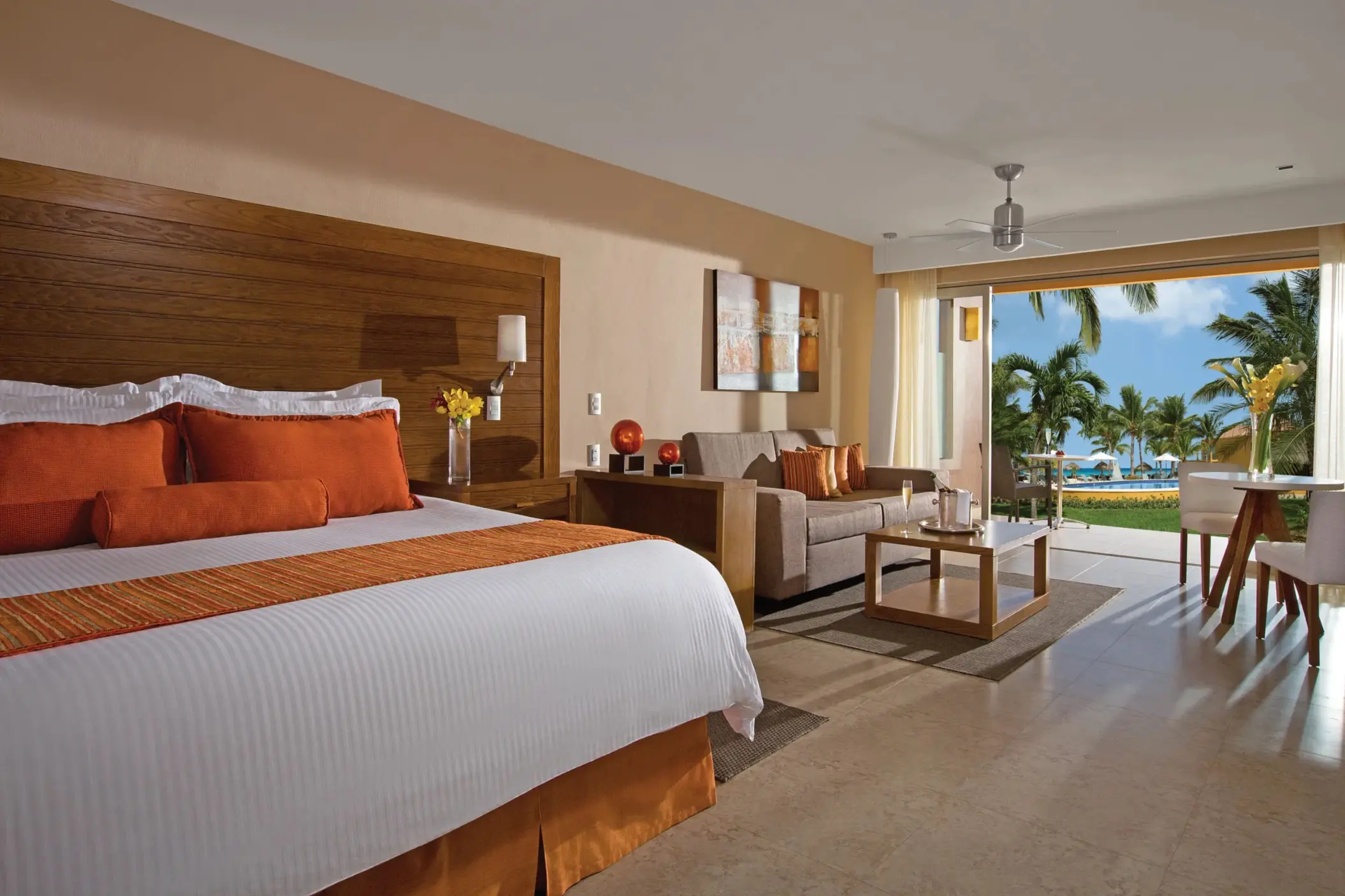 Preferred Club junior suite with king bed, stylish decor, and tropical pool view from patio.