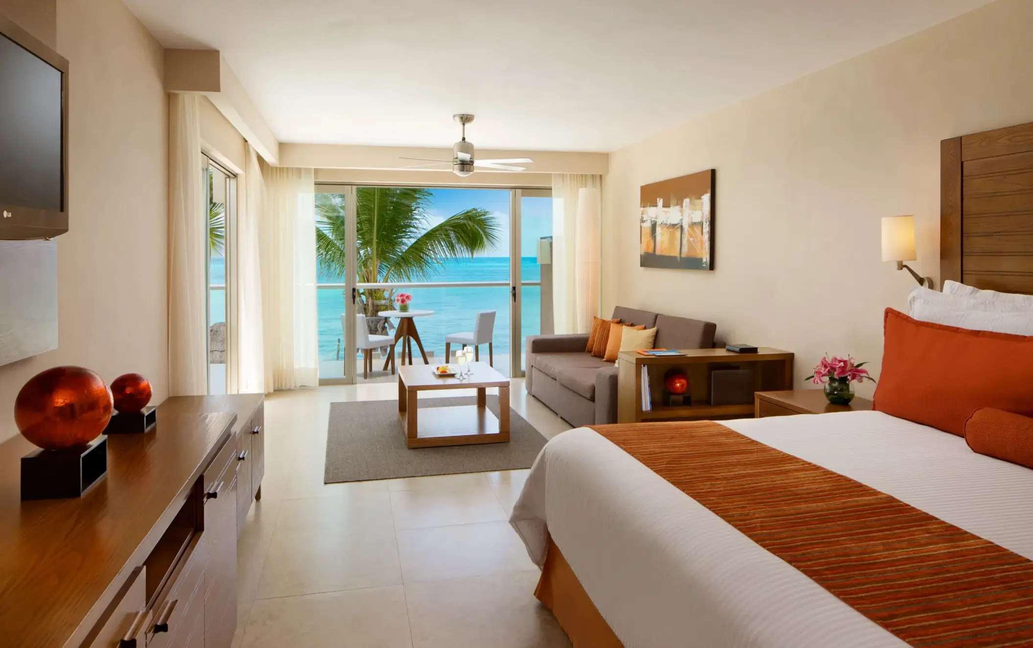 Oceanfront junior suite with king bed, bright decor, and private balcony overlooking the sea.