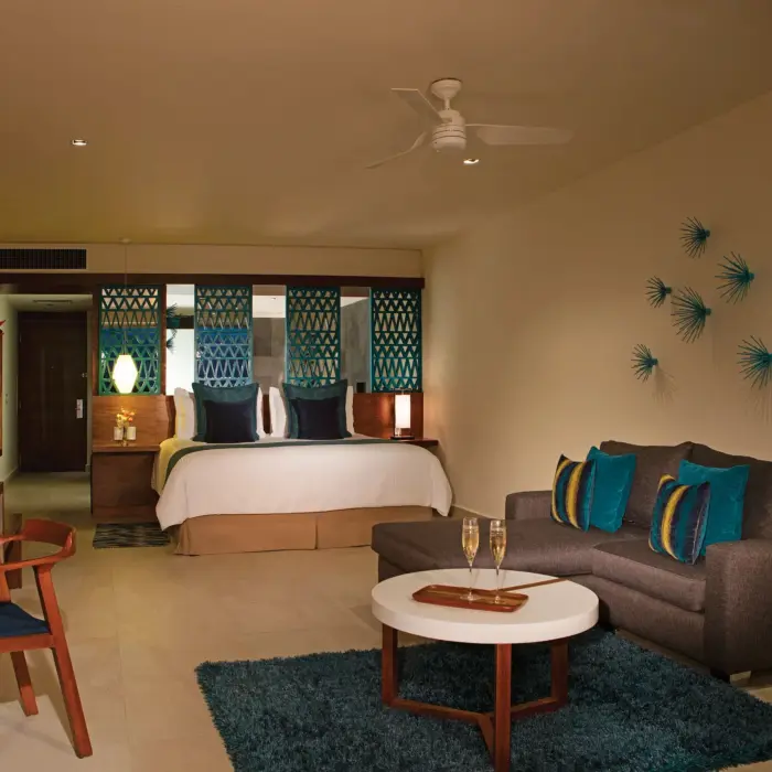 Spacious ocean view bedroom with teal accents, king bed, and cozy seating area in modern decor.
