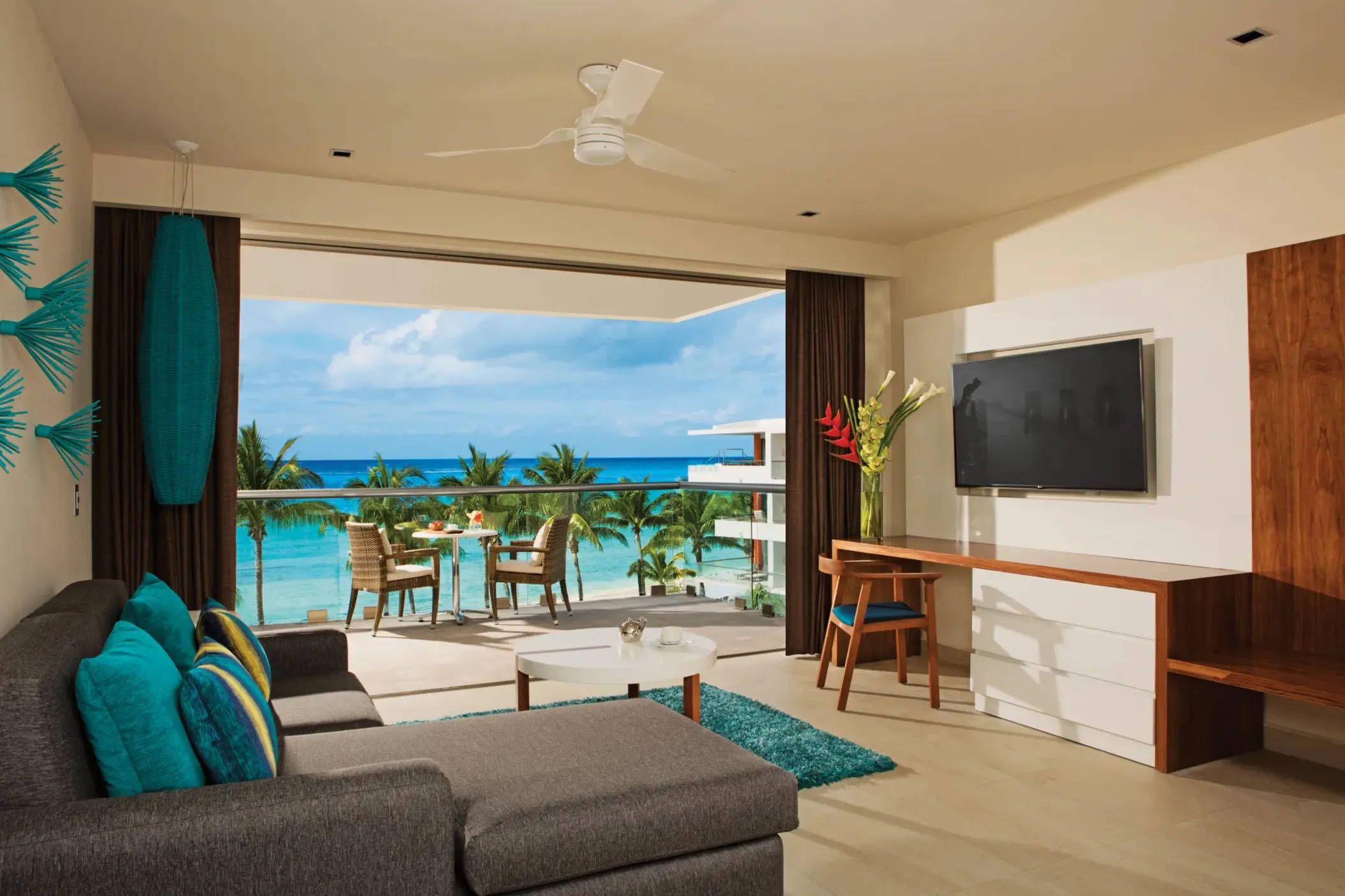 Living area with sofa, TV, and balcony seating offering ocean views and a relaxing atmosphere.