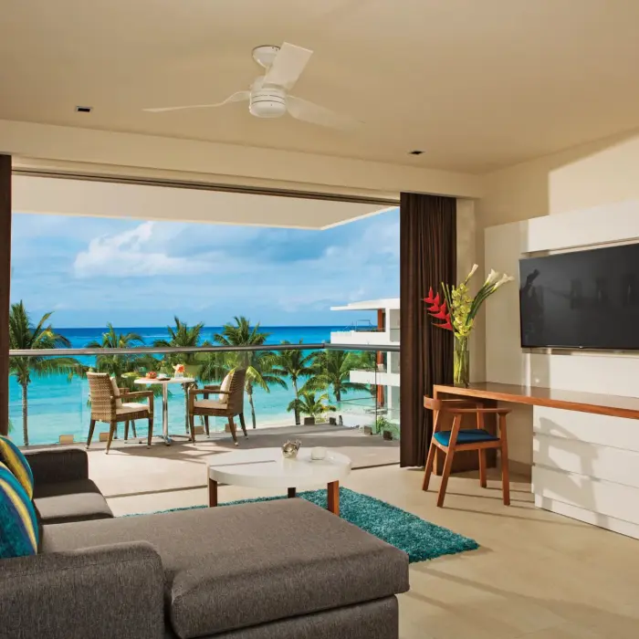 Living area with sofa, TV, and balcony seating offering ocean views and a relaxing atmosphere.