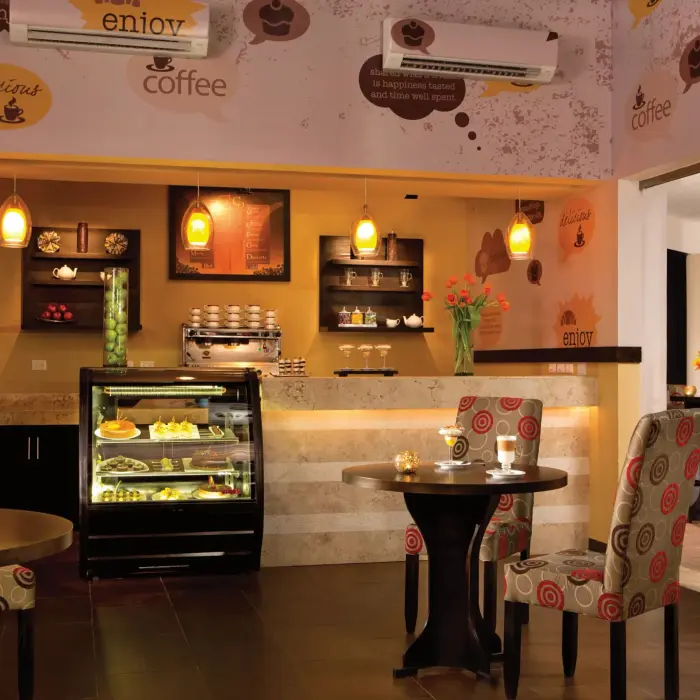 Cozy Coco Café with wooden furniture, pendant lighting, and a display of fresh pastries and coffee.
