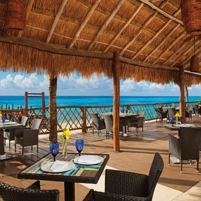 Elegant outdoor dining at Oceana with white tablecloths, ocean breeze, and Caribbean Sea views.
