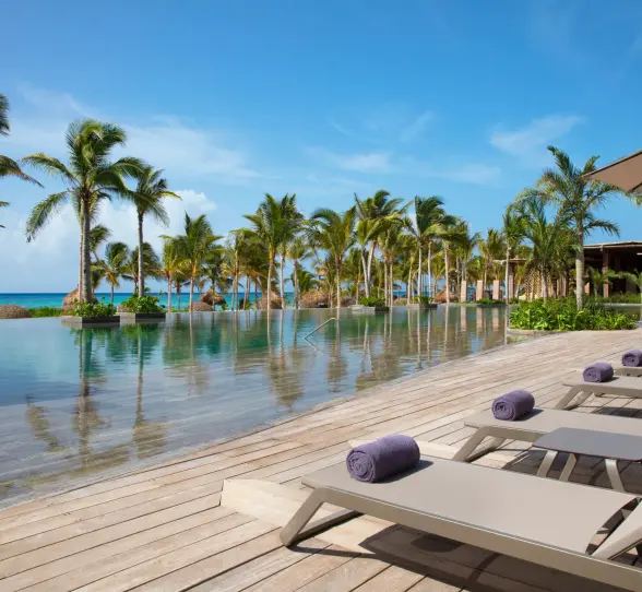 main infinity pool by the beach with loungers at Secrets Moxche Playa Del Carmen
