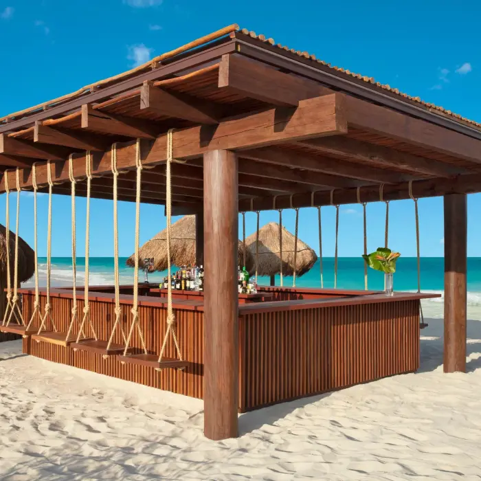 Beachfront swing bar with wood roof and tropical views, serving cocktails just steps from the sand.
