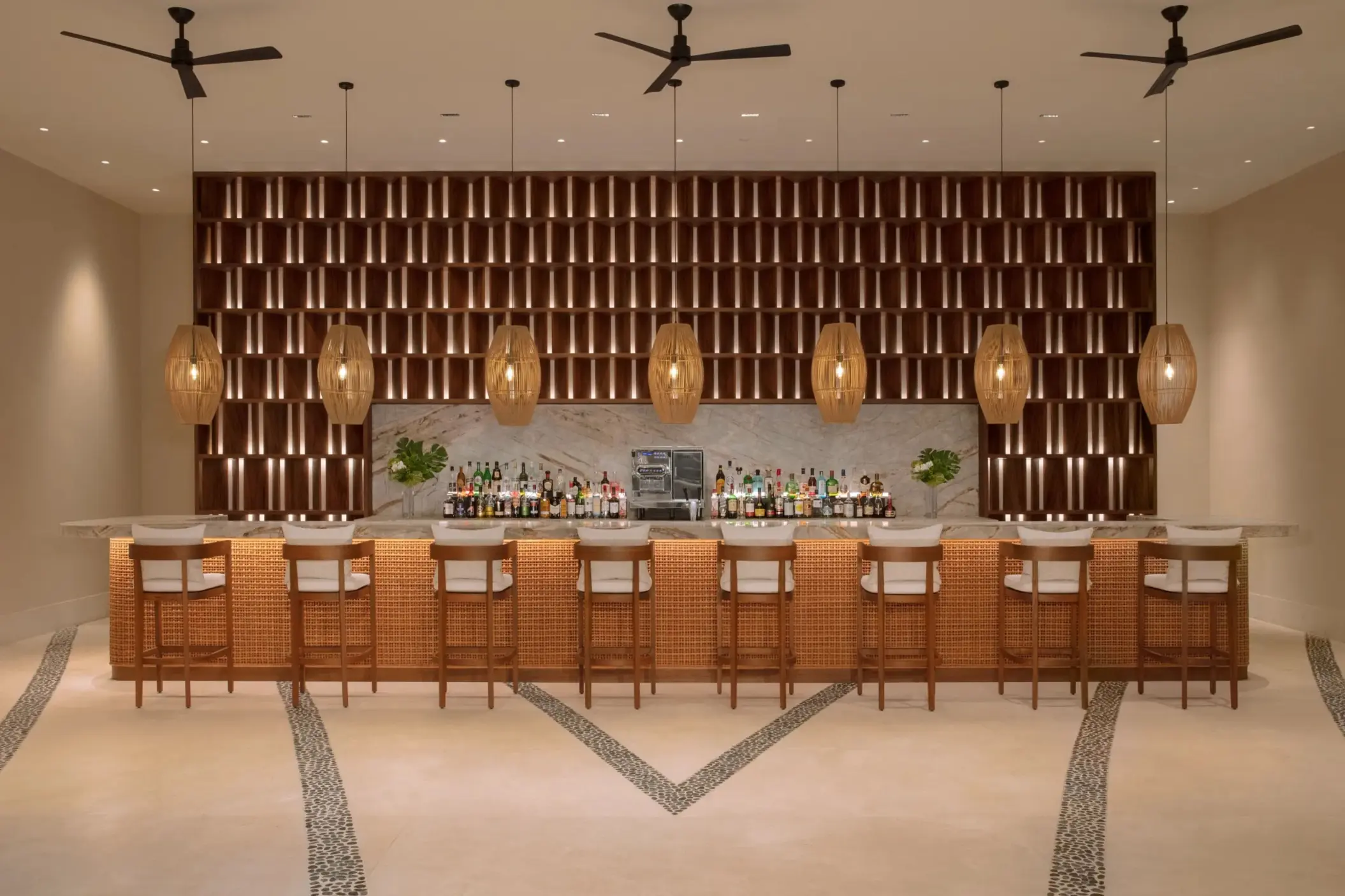 Elegant indoor bar with woven pendant lights and cushioned seating for upscale evening drinks.