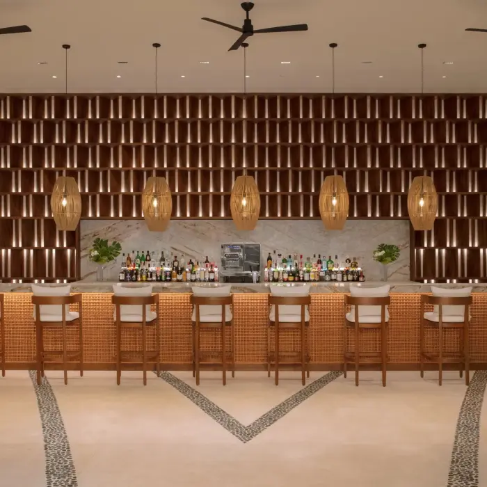 Elegant indoor bar with woven pendant lights and cushioned seating for upscale evening drinks.