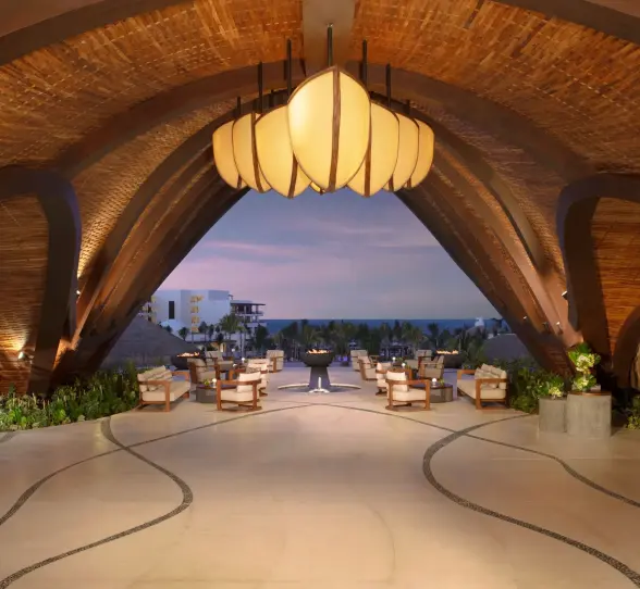 Striking resort lobby with sculptural wood ceiling and open-air views leading out to the ocean.
