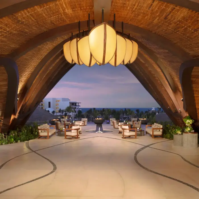 Striking resort lobby with sculptural wood ceiling and open-air views leading out to the ocean.