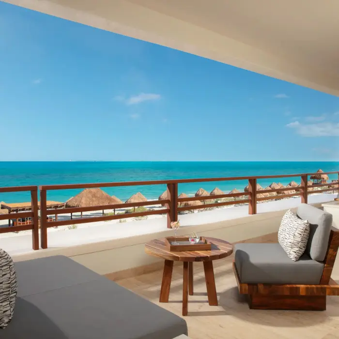 Expansive terrace with full ocean view, lounge beds, dining set, and wooden railing design.