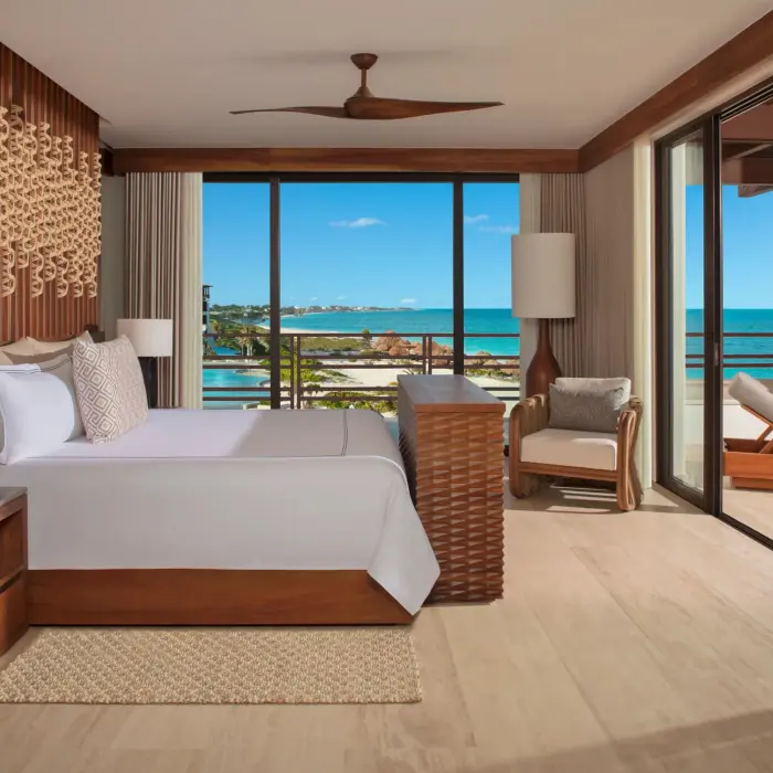 Oceanfront bedroom with king bed, neutral tones, and balcony offering expansive sea views.