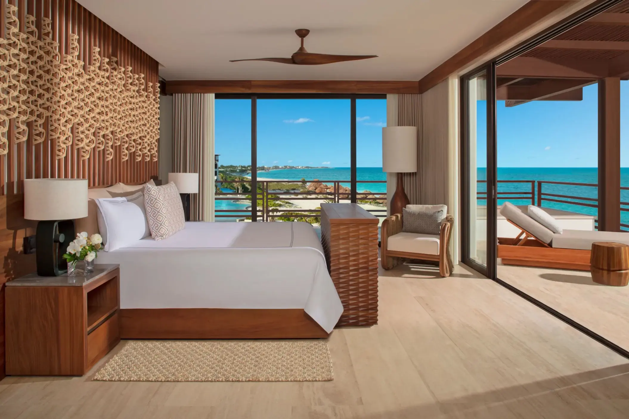 Oceanfront bedroom with king bed, neutral tones, and balcony offering expansive sea views.