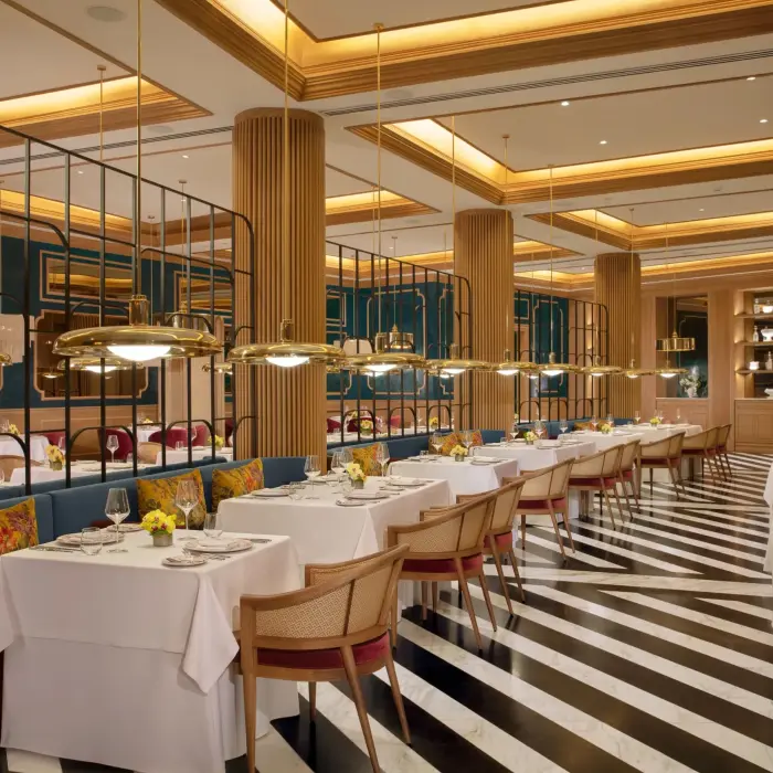 Elegant French restaurant Bordeaux featuring striped marble floors, gold lighting, and plush seating.