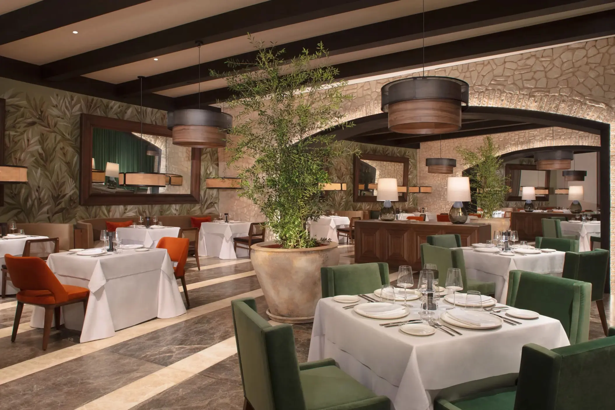 Elegant Italian restaurant interior with stone walls, greenery, and cozy seating under warm lighting.