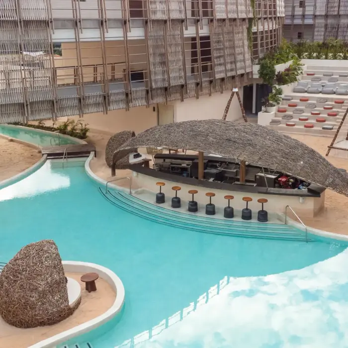 Open-air poolside bar with palapa roof, lounge seating, and a laid-back tropical vibe.