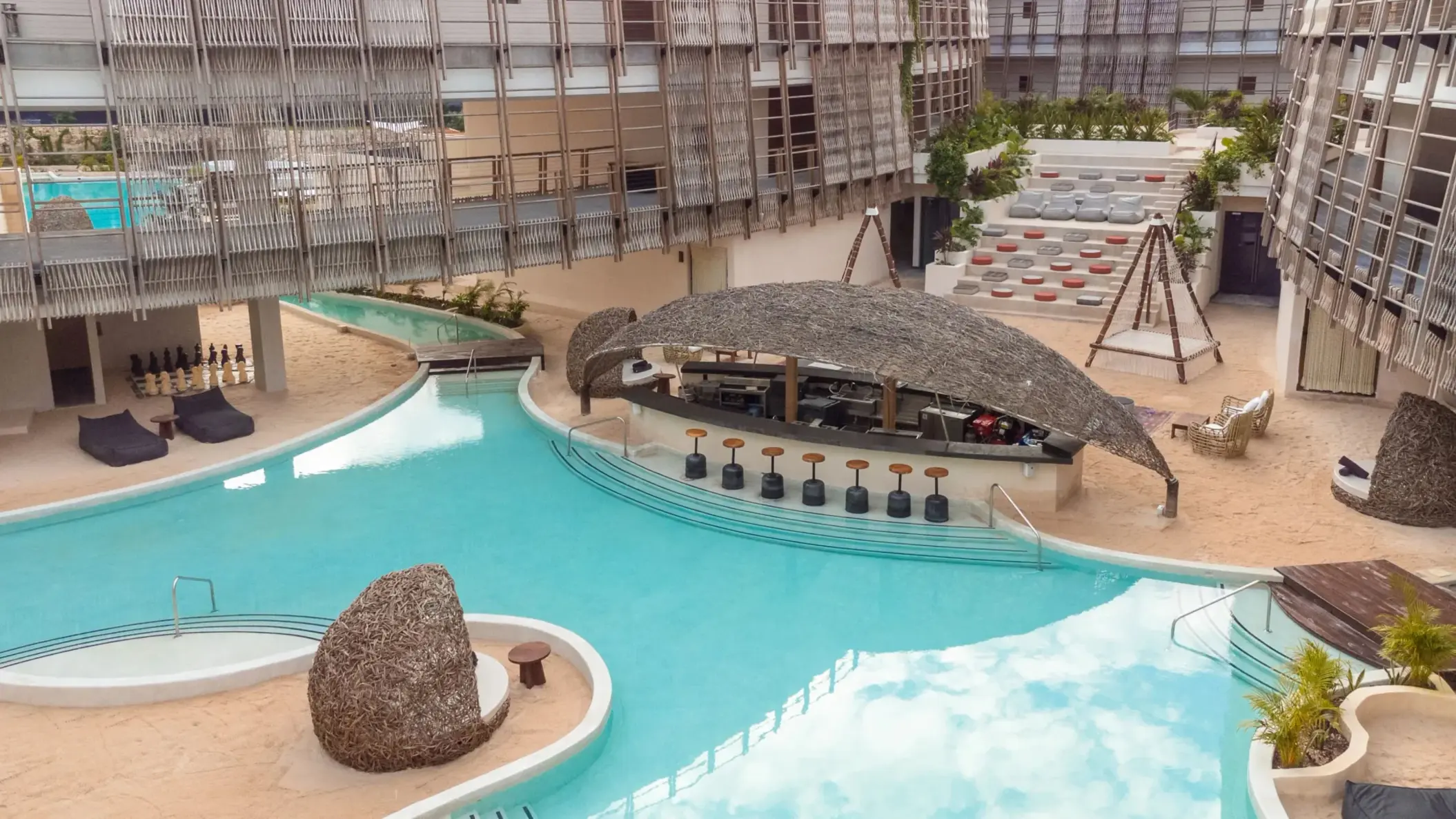 Open-air poolside bar with palapa roof, lounge seating, and a laid-back tropical vibe.
