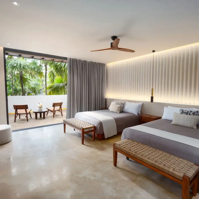 Double bedroom with crisp white linens, wooden furniture, and soft natural light.
