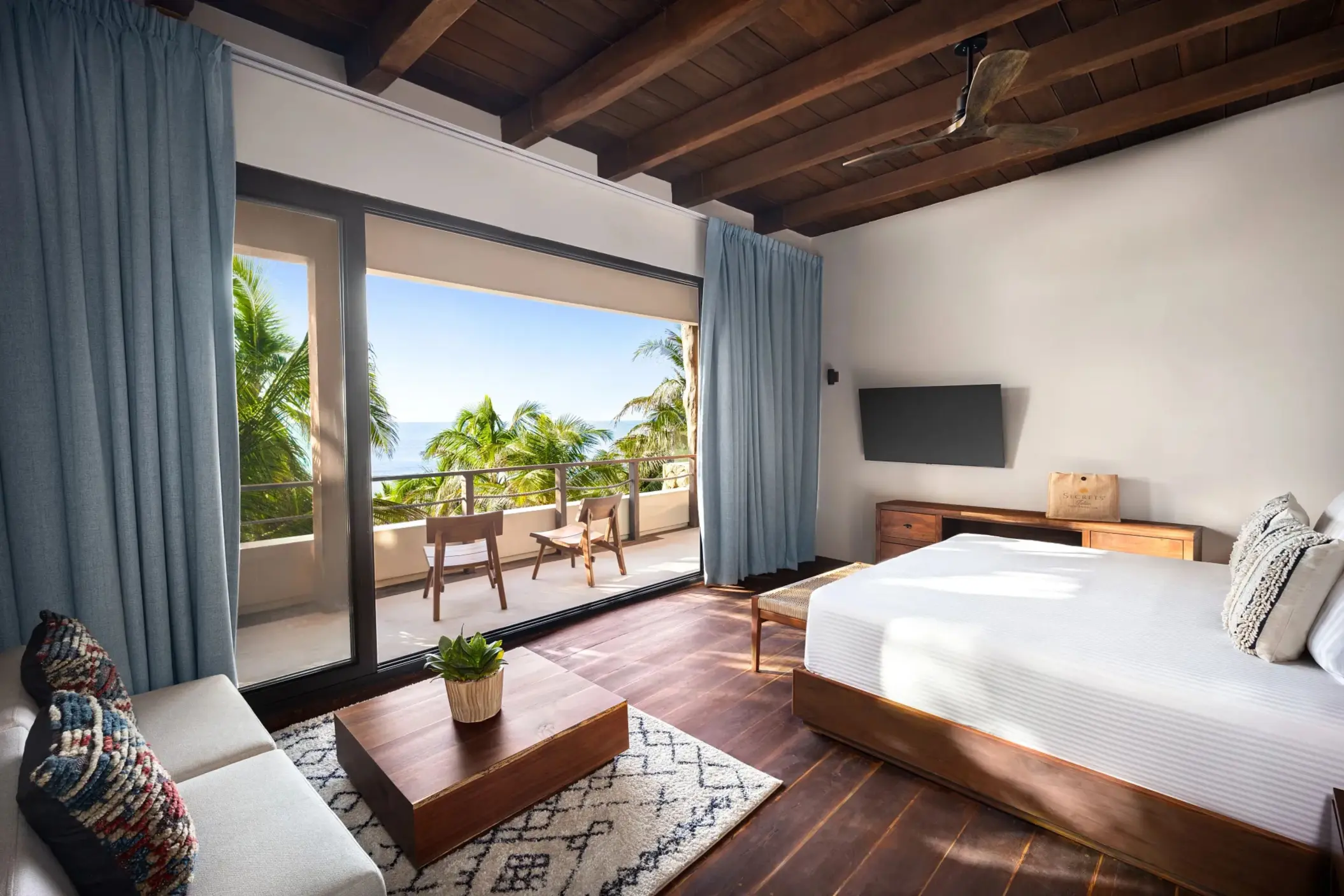 Cozy ocean-view bedroom with wood floors, beamed ceiling, modern decor, and open-air terrace.