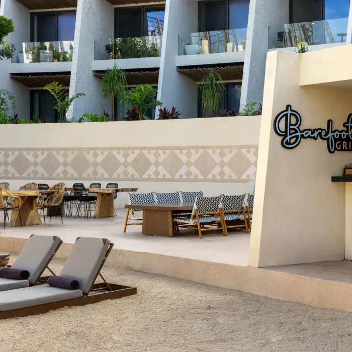 Open-air Barefoot Grill with wooden counters, shaded seating, and casual beachside atmosphere.