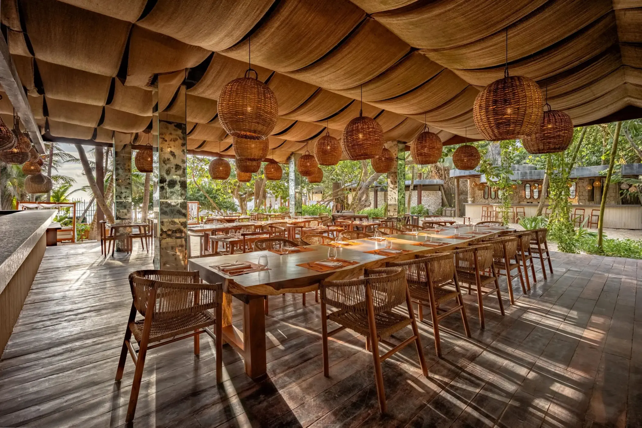 Beachfront Seaside Grill with wooden tables, ocean views, and relaxed open-air ambiance.