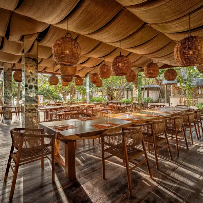 Beachfront Seaside Grill with wooden tables, ocean views, and relaxed open-air ambiance.