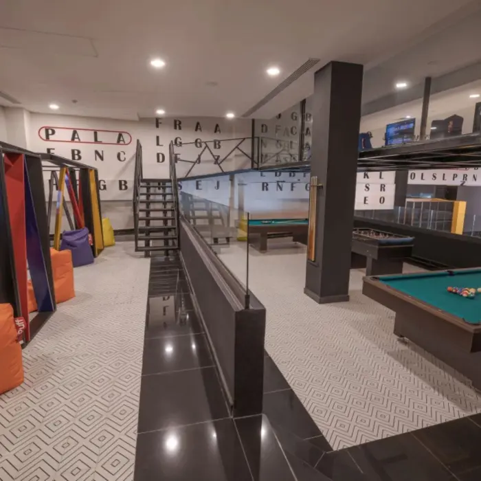 Game room with colorful bean bags, swings, pool table, and foosball setup at Sensira Riviera Maya.
