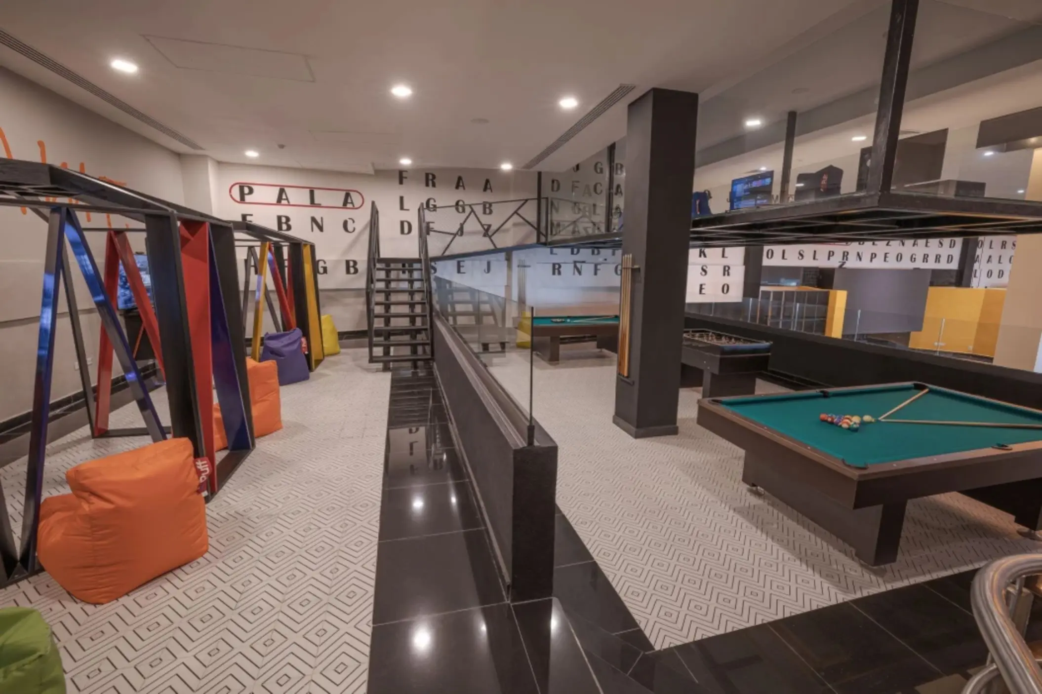 Game room with colorful bean bags, swings, pool table, and foosball setup at Sensira Riviera Maya.