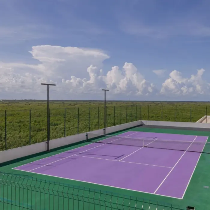 Purple tennis court surrounded by greenery under a bright blue sky at Sensira Resort.