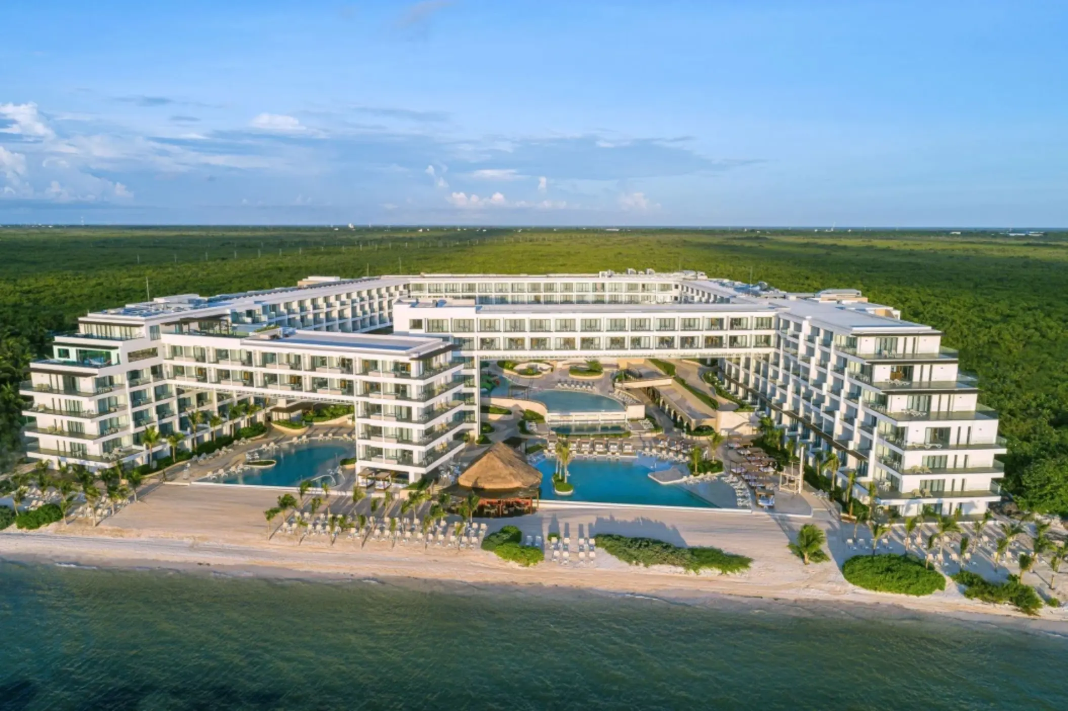 Aerial view of Sensira Riviera Maya surrounded by lush jungle and beachfront pools.
