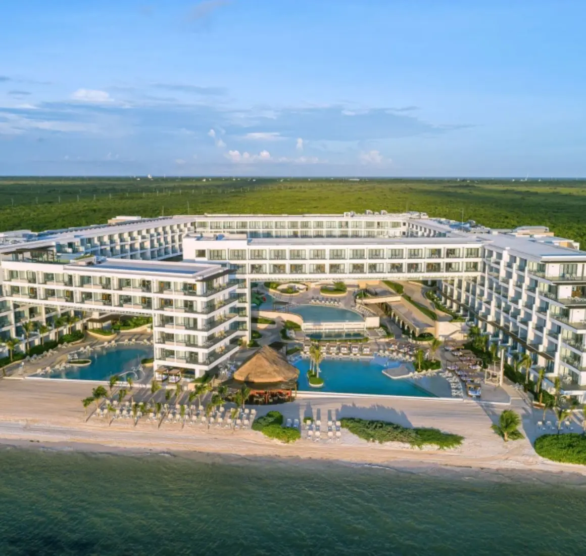 Aerial view of Sensira Riviera Maya surrounded by lush jungle and beachfront pools.